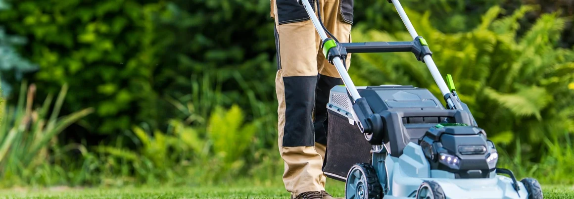 Person mäht Rasen mit Rasenmäher